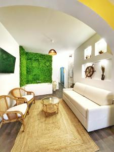 La suite Carthagène des Indes - centre ville , spa & terrasse privée في بيتون: غرفة معيشة مع أريكة بيضاء وجدار أخضر