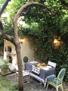 a patio with a table and chairs under a tree at Les renards du coeur (Le volpi del cuore) in Seravezza