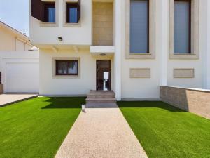 a house with a green lawn in front of it at Amazing frontline beach villa in Larnaca