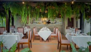 a restaurant with white tables and chairs and plants at Shintana Saya Residence in Siem Reap