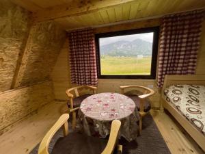 mesa y sillas en una habitación con ventana en Durmitor cottage in green field-Mountain cottage, en Žabljak