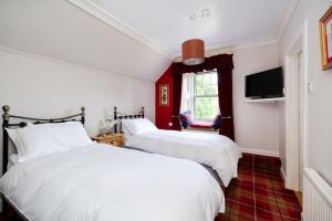 two beds in a room with red and white at Mansewood Country House in Lochearnhead