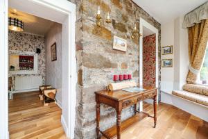 a room with a stone wall and a wooden table at Mansewood Country House in Lochearnhead