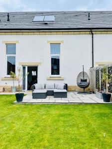 un patio con 2 sofás frente a una casa en The Old Schoolhouse, Kinross en Kinross