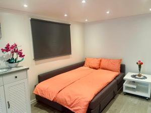 1 dormitorio con 1 cama con manta naranja en Fint gjesterom med bad og kjøkken til leie nær EB stranda med en Arendal