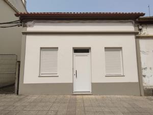 a white garage with a door and two windows at Areas Negras. Casas de Fanego. in Cariño