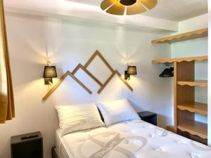 a bedroom with a bed with two lights on the wall at Appartement rénové 2 chambres vue pistes parking privatif in Les Orres