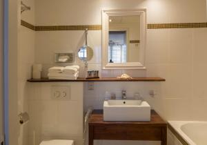 ein weißes Badezimmer mit einem Waschbecken und einem Spiegel in der Unterkunft Noordzee, Hotel & Spa in Cadzand-Bad