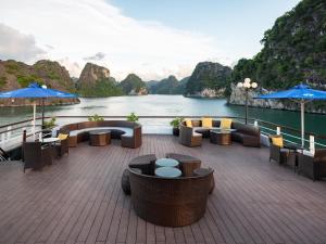 eine Terrasse mit Tischen und Stühlen und Blick auf das Wasser in der Unterkunft M'Gloria Cruise in Hạ Long