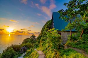 a house on a hill next to the water at sunset at Marco Polo Sarpi in Batumi