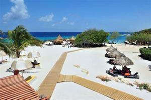 a group of people laying on a beach with umbrellas at Villa Curazon met privézwembad vlakbij het strand! in Jan Thiel