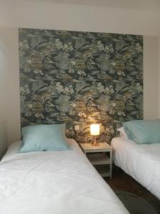 1 dormitorio con 2 camas y pared con papel pintado en L'ÉCHAPPÉE BELLE, en Capdenac-Gare