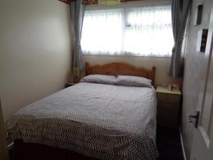 1 dormitorio con 1 cama con edredón a rayas y ventana en 204 BELLE AIRE, en Hemsby
