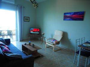 a living room with a couch and a table and a tv at TSOUMAS HOUSE in Kastrosikia