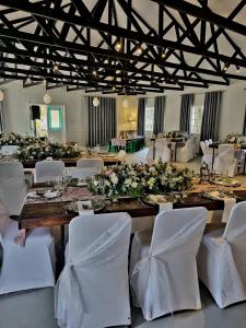 a large wooden table with white chairs and flowers at Silver Mist Guest House, Country Inn and Herberg in Kaapsehoop