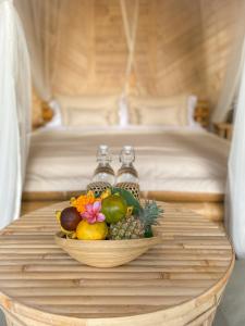 a bowl of fruit on a table in front of a bed at Wahem Eco Bamboo - Wahem Tebenan in Ubud
