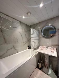 een badkamer met een wastafel, een bad en een spiegel bij Padriku Apartment with a balcony,near to central,Self Check In 24 7,FREE Parking in Tallinn