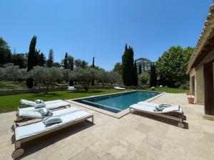 dwa leżaki i basen na dziedzińcu w obiekcie MAS MILLÉSIME - Chambre double - petit déjeuner - piscine - Mas du XVIIIème siècle proche Saint-Rémy-de-Provence w mieście Mas blanc des Alpilles