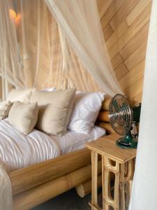a bedroom with a bed with a fan and a table at Wahem Eco Bamboo - Wahem Tebenan in Ubud +30 photos