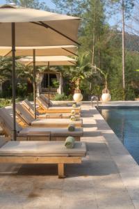 a row of lounge chairs with umbrellas next to a pool at IZZ Getaway - Adults Only in Göcek