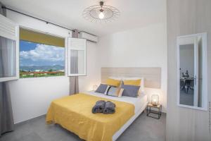 ein Schlafzimmer mit einem Bett mit einer gelben Decke und einem Fenster in der Unterkunft Navira - Appartement le Pavillon in Le Lamentin