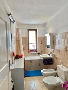 łazienka z toaletą, umywalką i wanną w obiekcie Chasa Sassalbo w mieście Poschiavo