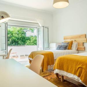 a white room with two beds and a window at Lisbon Blue House in Oeiras
