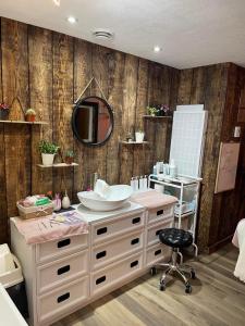 baño con lavabo, espejo y silla en Le Saint Alex, en Saint-Alexis-des-Monts