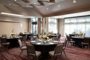 una sala de conferencias con mesas, sillas y ventanas en Courtyard by Marriott San Francisco Airport, en San Bruno