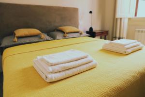 two towels are stacked on top of a yellow bed at Firenze House Zanella in Florence