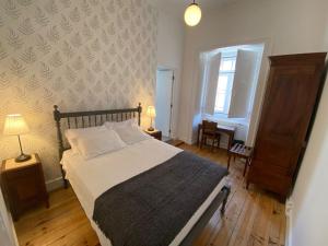 a bedroom with a bed and a table and a window at União - Guest House in Tomar