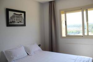 ein Schlafzimmer mit einem weißen Bett und einem Fenster in der Unterkunft Appt 22 Bloc G- Hicherraton plage Residence Bella Vista, BOUZNIKA BAY in Skhirat