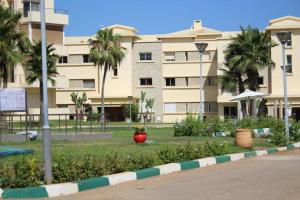 a large building with palm trees in a park at Appt 22 Bloc G- Hicherraton plage Residence Bella Vista, BOUZNIKA BAY in Skhirat