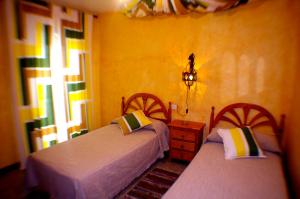 two beds in a room with yellow walls at Pensión El Alamo in Lepe