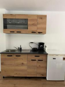 a kitchen with wooden cabinets and a sink and a refrigerator at Cabana Muntelui in Munteni