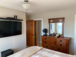 a bedroom with a dresser and a flat screen tv at Dragonfly Inn Loft & Walkout Suites in Sherwood Park