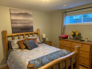 a bedroom with a bed and a dresser and a window at Dragonfly Inn Loft & Walkout Suites in Sherwood Park