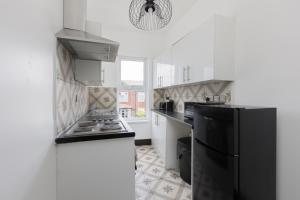 a kitchen with a black refrigerator and white cabinets at Prism Everyday - One Bed Apartment in Blackpool