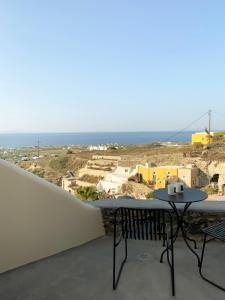 balcón con mesa y vistas al océano en Ambelia Traditional Villas, en Oia