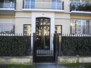 a white house with a black door and fence at Apt Standing Bordeaux Chartrons in Bordeaux