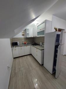 a kitchen with white cabinets and white appliances at Casa Cristina in Cârțișoara