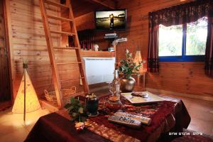 una sala de estar con una mesa en una cabaña en אלאדין בקתות ומערות - נופש כפרי קסום ליד הכנרת עם מקלט צמוד, en Had Nes