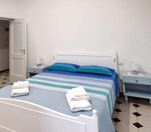Un dormitorio blanco con una cama con toallas. en Dimora Torre del Cavaliere, en Castro di Lecce