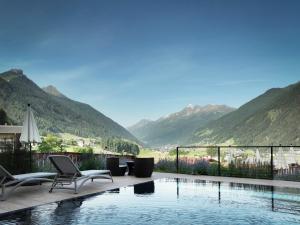 una piscina con sedie e vista sulle montagne di LifestylePanoramaHotel Erika Superior a Neustift im Stubaital