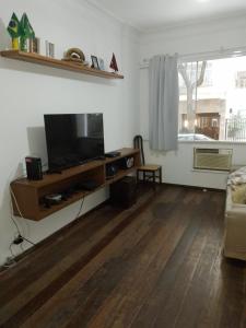 sala de estar con TV de pantalla plana y suelo de madera. en Apt inteiro 1 minuto da praia, en Río de Janeiro