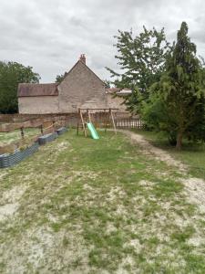 un patio con columpio frente a un edificio en Ferme Des Chapelles, en Fresnes-en-Tardenois