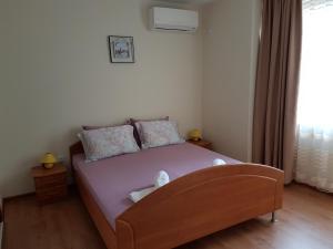 ポモリエにあるVeleka Apartmentsのベッドルーム1室(紫のシーツが敷かれたベッド1台、窓付)