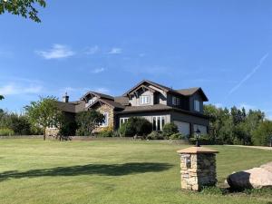 a large black house on a green lawn at Dragonfly Inn Loft & Walkout Suites in Sherwood Park