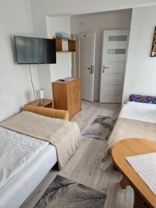 a room with two beds and a table and a tv at Stella Maris in Karwia