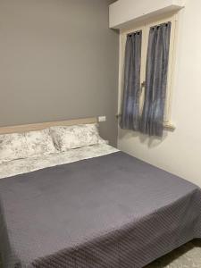 a bedroom with a bed with a gray bedspread and a window at Appartamento per vacanze in Porto SantʼElpidio